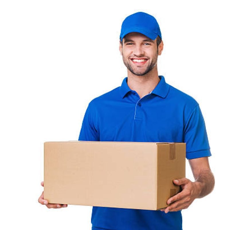 Happy young courier holding a cardboard box and smiling while standing against white background